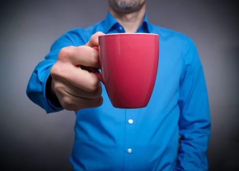 Business man holding a red cup of coffee, selective focus on the foreground