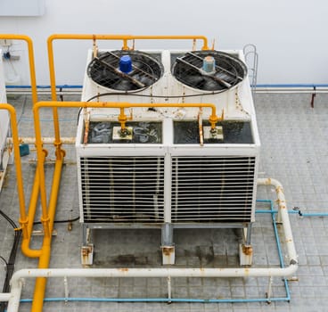 Industrial cooling towers or air cooled water chillers with piping system on building rooftop