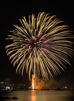 Big yellow firework on the sky at Pattaya coast with cityscape background, Thailand