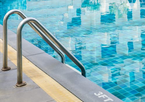 Swimming pool with metal handrail stair