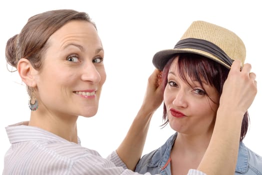 two happy female friends trying  hats