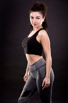 pretty brunette wearing fitness outfit on dark black background