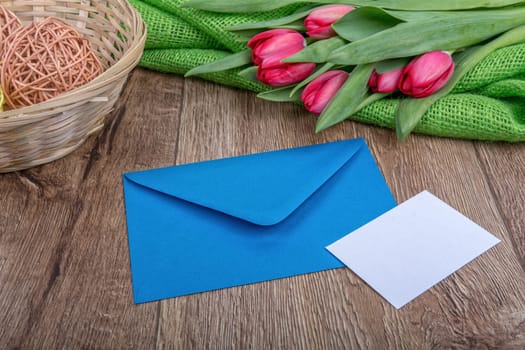 Envelope with sheet of paper and red tulips on a wooden background