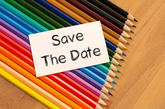 Save the date text concept and colored pencil on wooden background