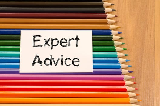 Expert advice text concept and colored pencil on wooden background
