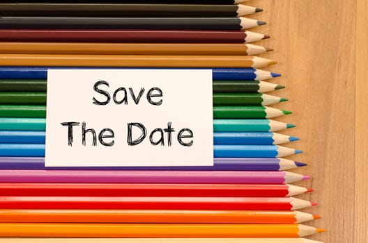 Save the date text concept and colored pencil on wooden background