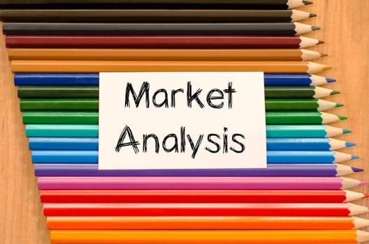 Market analysis text concept and colored pencil on wooden background