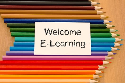 Welcome e-learning text concept and colored pencil on wooden background