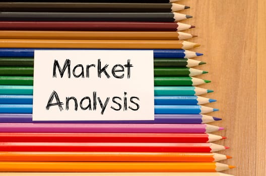 Market analysis text concept and colored pencil on wooden background