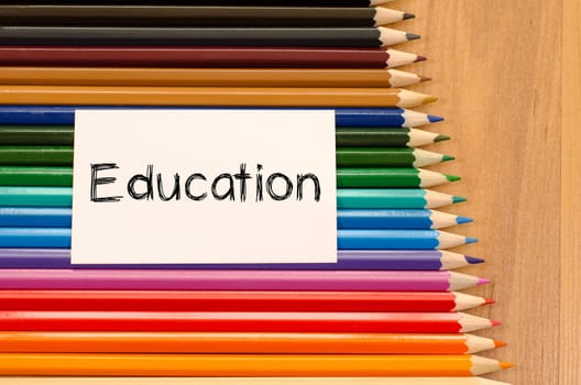 Education text concept and colored pencil on wooden background