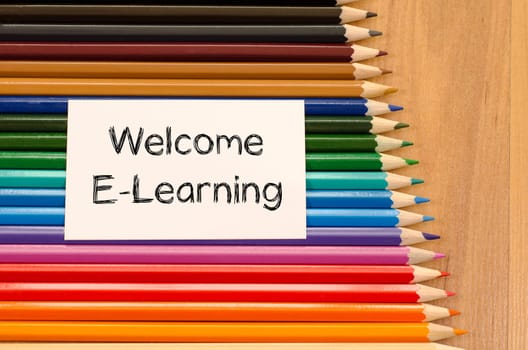 Welcome e-learning text concept and colored pencil on wooden background