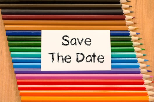 Save the date text concept and colored pencil on wooden background
