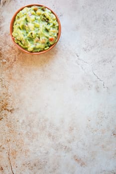 Bowl of fresh guacamole  n stone surface with copy space and viewed from above.