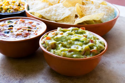 Bowl of fresh guacamole, with chips and salsa ready to eat.