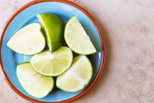 Close up of lime wedges on blue plate with copy space, view from above.