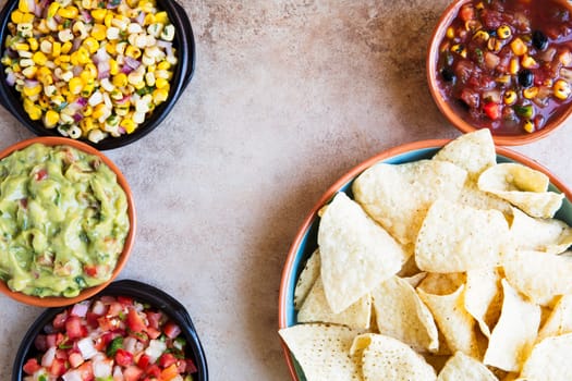 Tortilla chips served with guacamole, salsa, and pico de gallo with copy space, view from above.