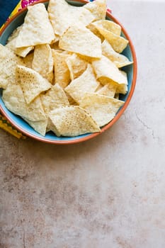Bowl of fresh tortilla chips on stone surface with copy space.  View from above