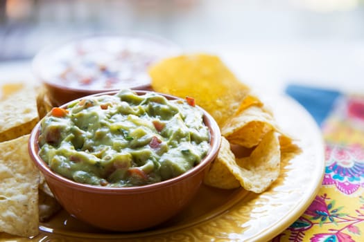 Fresh guacamole in a bowl with tortilla chips