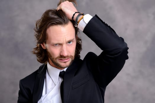 portrait of a young stressed business man in black suit