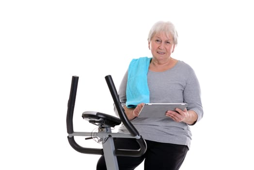 gray-haired female senior train with fitness machine and using tablet PC