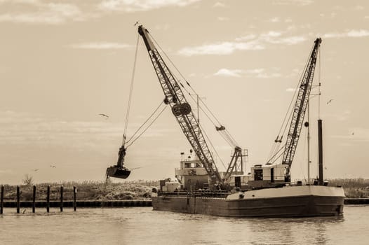 Vintage Effect. Small dredge marine,which is cleaning a navigation channel