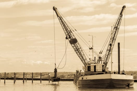 Vintage Effect. Dredger ship navy working to clean a navigation channel