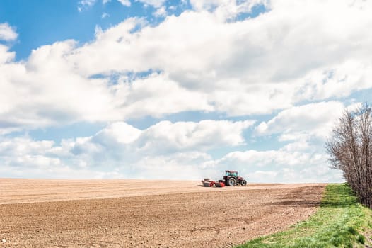 Farm work. Tractor compresses the soil after planting with rollers.