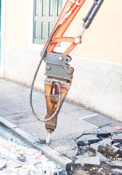 Large pneumatic hammer mounted on the hydraulic arm of a construction equipment