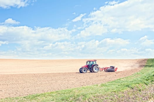 Farm work. Tractor compresses the soil after planting with rollers.