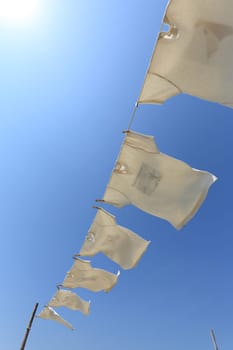 White laundry hanging on the clothesline against blue sky