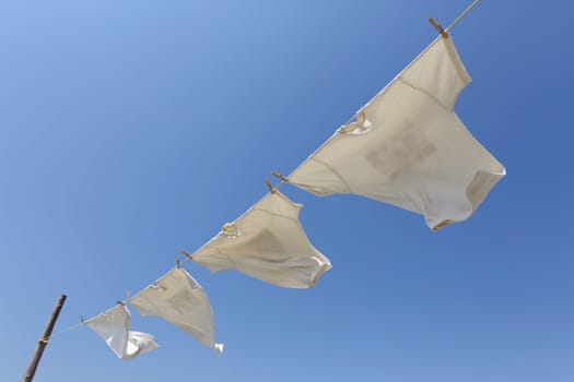 White t-shirts hanging on the clothesline against blue sky