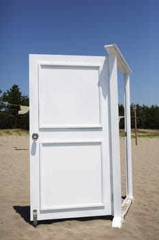 White door on the sand against blue sky