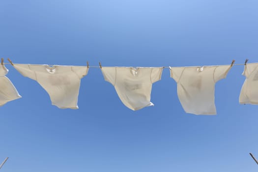 White t-shirts hanging on the clothesline against blue sky