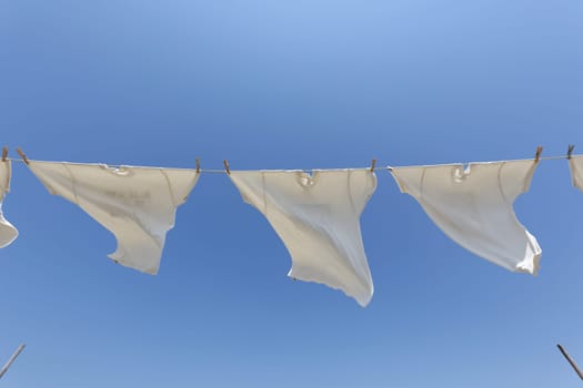White t-shirts hanging on the clothesline against blue sky