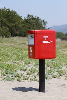 Red Japanese mail box on a sandy beach