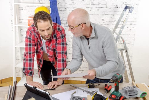 two technicians read a plan in the workshop