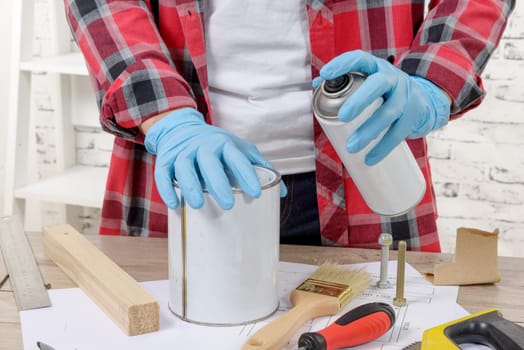 A young man with aerosol paint and blue gloves