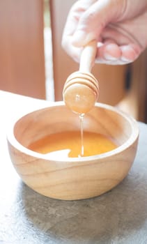 Hand on honey dipper from wooden cup, stock photo