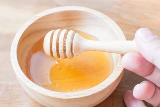 Hand on honey dipper from wooden cup, stock photo