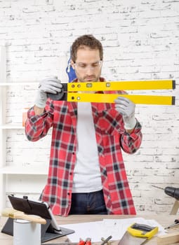 young man viewing a spirit level,  to read the position of the bubble to ensure a horizontal line