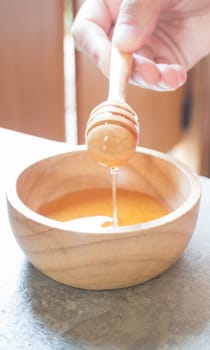 Hand on honey dipper from wooden cup, stock photo