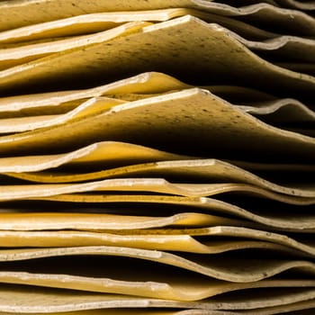 An up close view of the corners of un cooked pieces of lasagne all stacked one on top of the other.