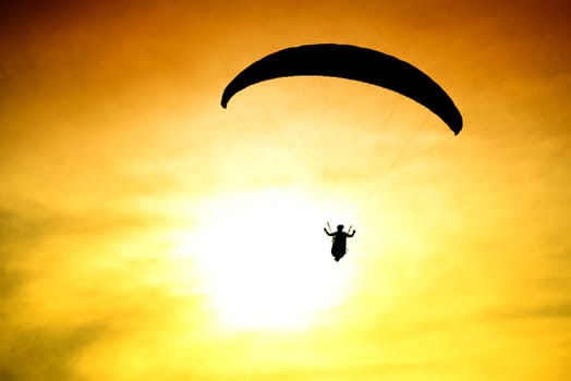 Silhouette of parachute on sunset background