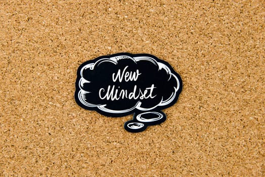 New Mindset written on black thinking bubble over cork board background, copy space available