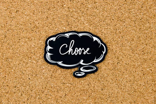 CHOOSE written on black thinking bubble over cork board background, copy space available
