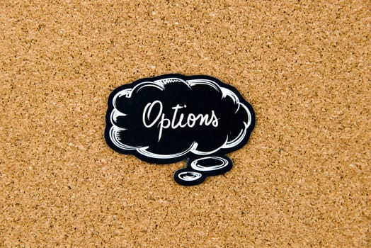 OPTIONS written on black thinking bubble over cork board background, copy space available
