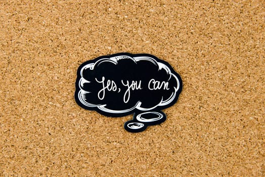 YES, YOU CAN written on black thinking bubble over cork board background, copy space available
