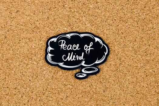 PEACE OF MIND written on black thinking bubble over cork board background, copy space available