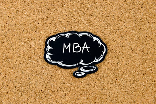MBA written on black thinking bubble over cork board background, copy space available