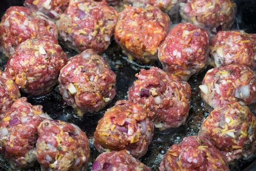 Italian style meatballs cooking on a pan